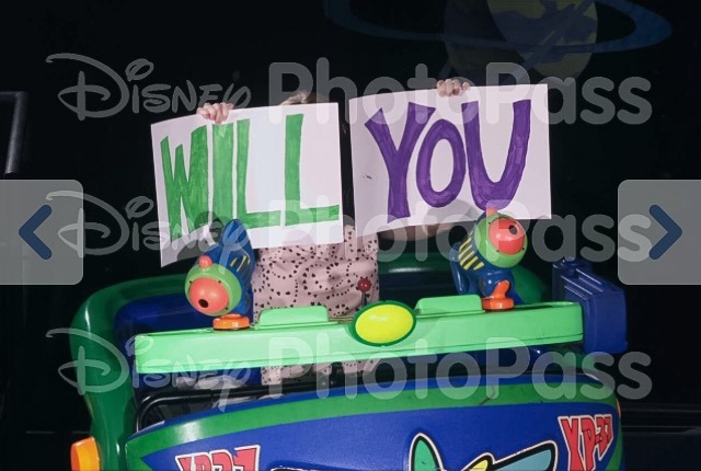 Photopass photo of Kirsten holding the "Will" and "You" signs on Buzz Lightyear.