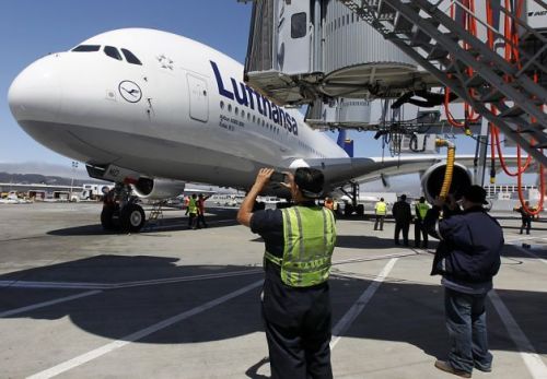 Ground crew personnel snap photos of a Lufthansa Airbus A380...