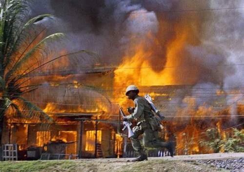 greasegunburgers - A U.S. trooper runs past a burning building in...