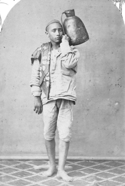 Portrait of a young Algerian man posing with a jug, c....