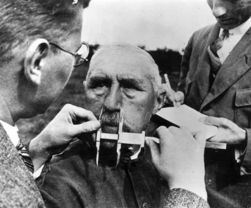 historicaltimes - A man has his nose measured as part of Aryan...