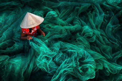 sixpenceee - A woman creates a fishing net in a small village near...
