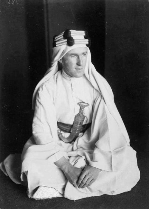 warhistoryonline - Lawrence in Arab dress seated on the ground,...