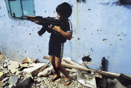 historicaltimes - A Palestinian child plays with an AK assault...
