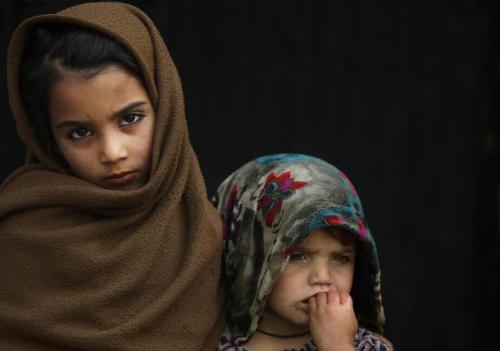salamalaikum - An Afghan refugee girl, left, looks on while...