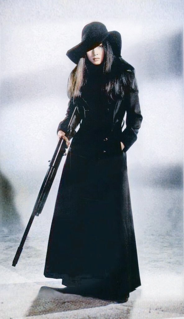 黒いロングコートに黒い帽子をかぶっているライフル銃を持った梶芽衣子の画像