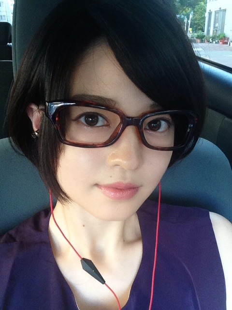 黒ぶち眼鏡をかけてイヤホンをしている小林涼子の画像