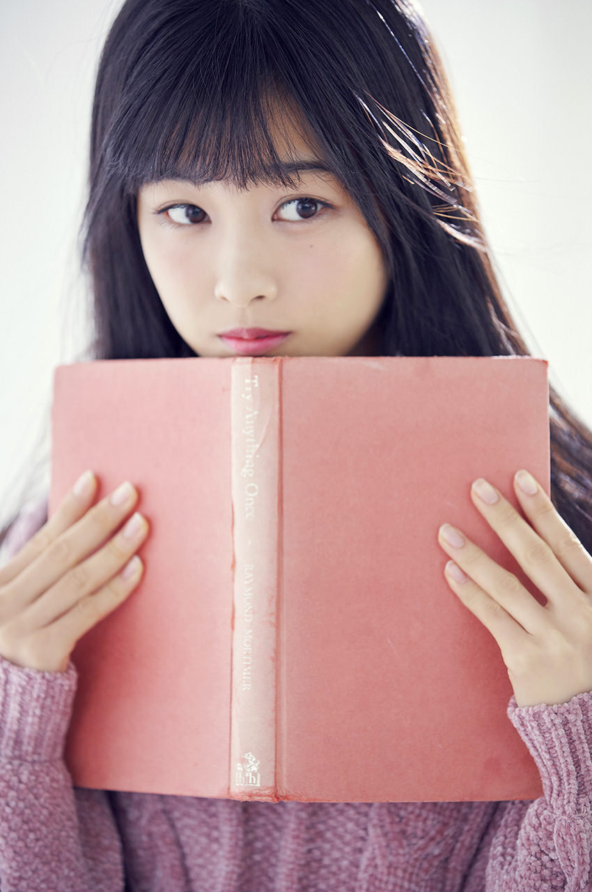 ピンクのニットワンピを着た本を持っている原田葵の画像