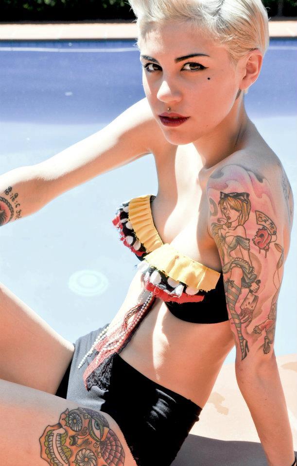 mujer con tatuajes en el hombro posando en la piscina