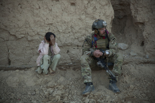 airbornebear:A boy sits near a coalition force member during a...
